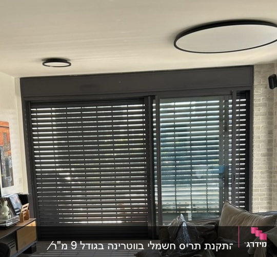 תריסי אלומיניום כהים על חלון זכוכית גדול
